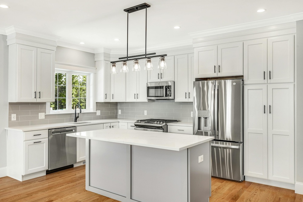 Modern kitchen with light colored cabinetry, a center island, marble countertops, and stainless steel appliances.