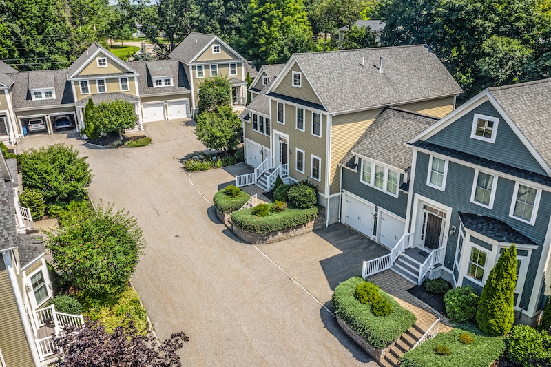 Aerial view of a small neighborhood with tan houses and well maintained shrubbery.